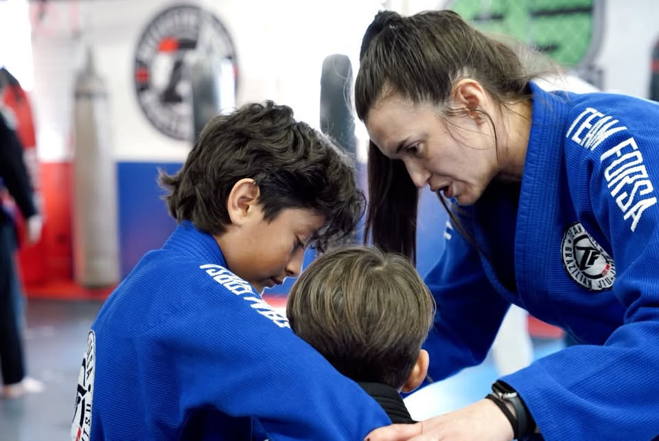 Coach teaching technique to two young students at Ippon Sports Academy
